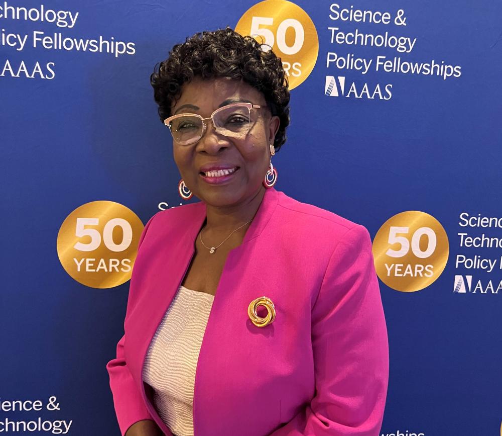 STPF alum Stella Uzogara posing in front of a dark blue STPF backdrop.