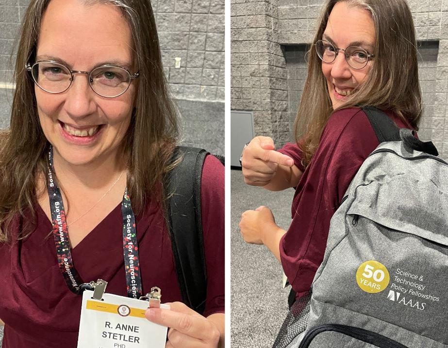 STPF fellow R. Anne Stetler posting with her SFN2023 conference badge, as well as a grey backpack with the STPF 50th anniversary logo on it.