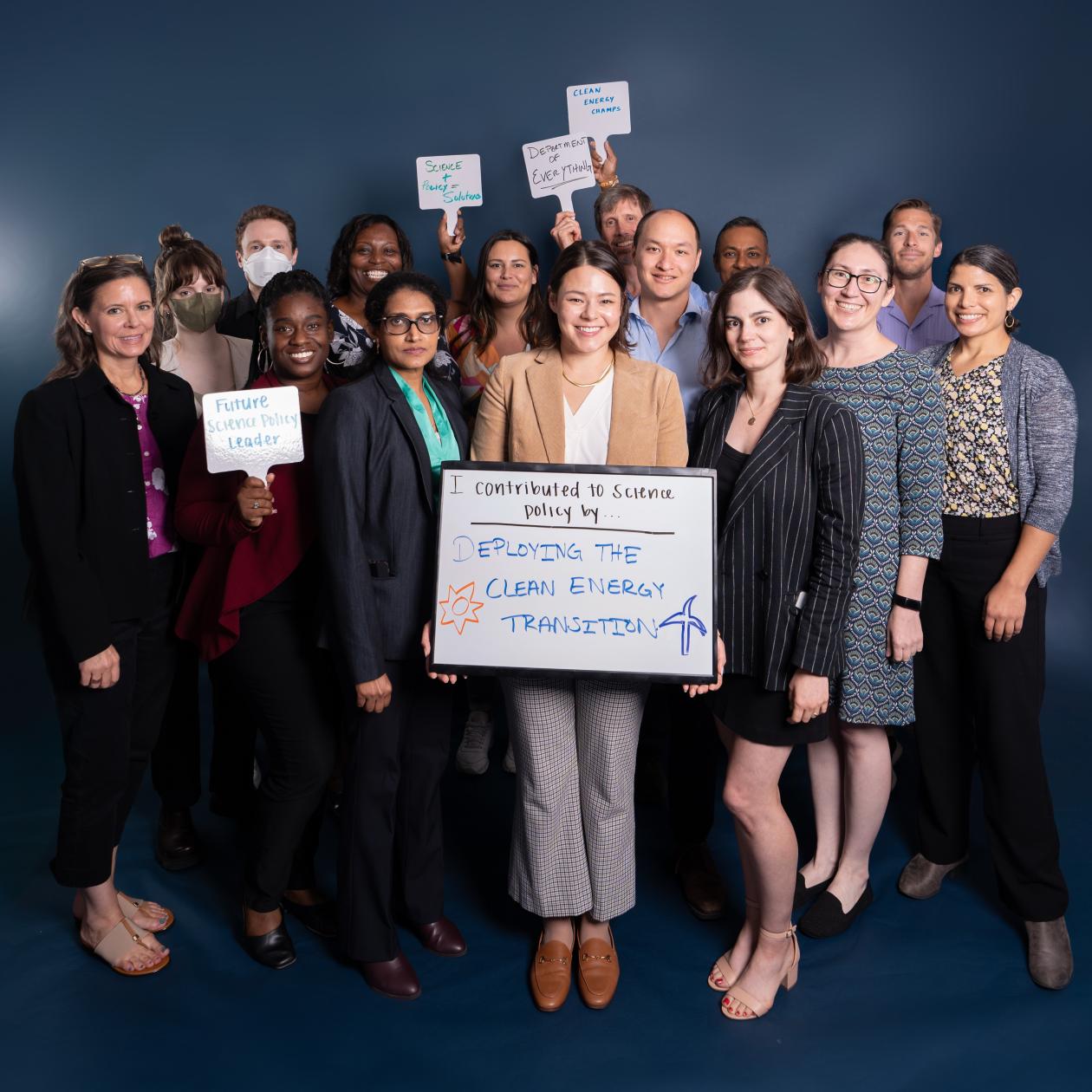 Fellows taking a group photo holding white board signs that say how they've impacted science policy.
