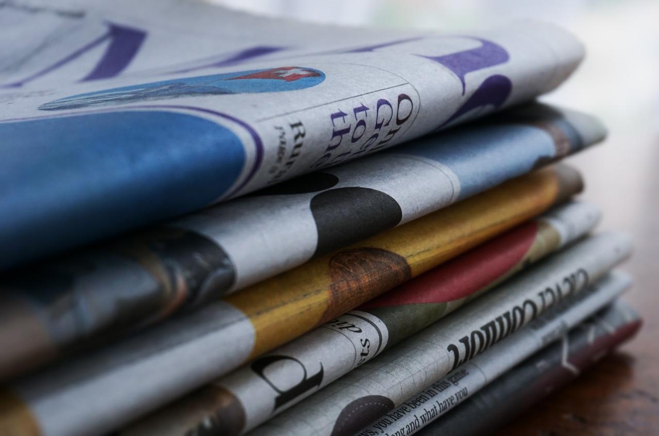 Stack of folded newspapers, by Suzy Hazelwood.