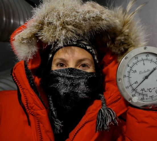 Photo of Nature McGinn out in the field, wearing a thick red winter coat. 