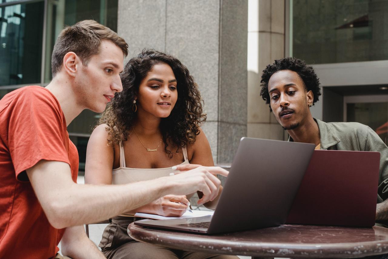 Three people sitting around a laptop