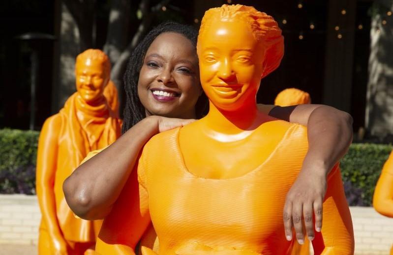 Lekelia Jenkins posing with her orange statue at the Smithsonian