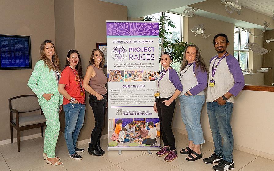 Dr. Chrissy Cross and Dr. Marisol Diaz, and other members of the Project RAICES team, stand in front of a banner