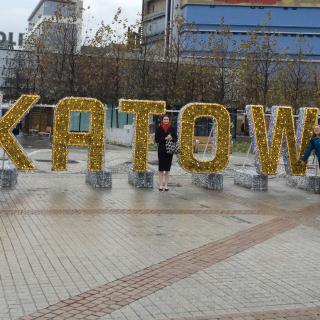 STPF alum fellows in front of a sign of Katowice, Poland. Image by Gillian Bowser (featuring Nycole Scheverria, Shelby Mcclelland and Sarah Whipple)