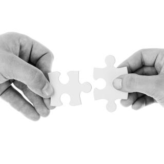 Black and white photos of two hands holding puzzle pieces next to each other.