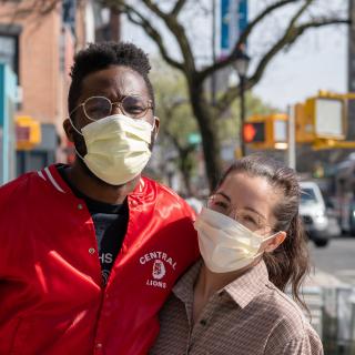 Two people wearing masks hugging and smiling at the camera, Julian Wan, Unsplash