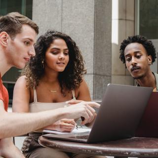 Three people sitting around a laptop